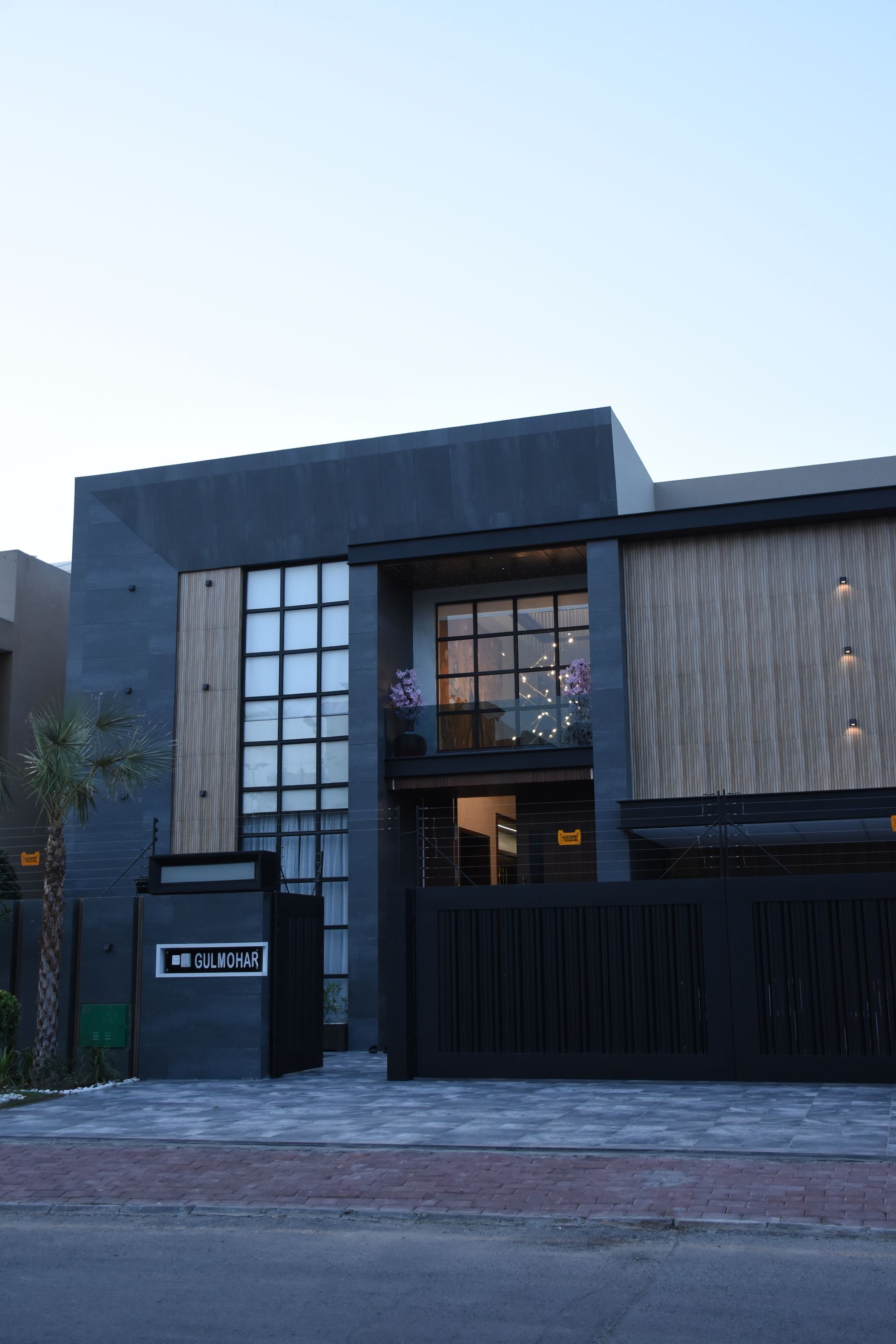 Contemporary two-storey house in Lahore with a dark stone facade, wood slats, and a black metal gate