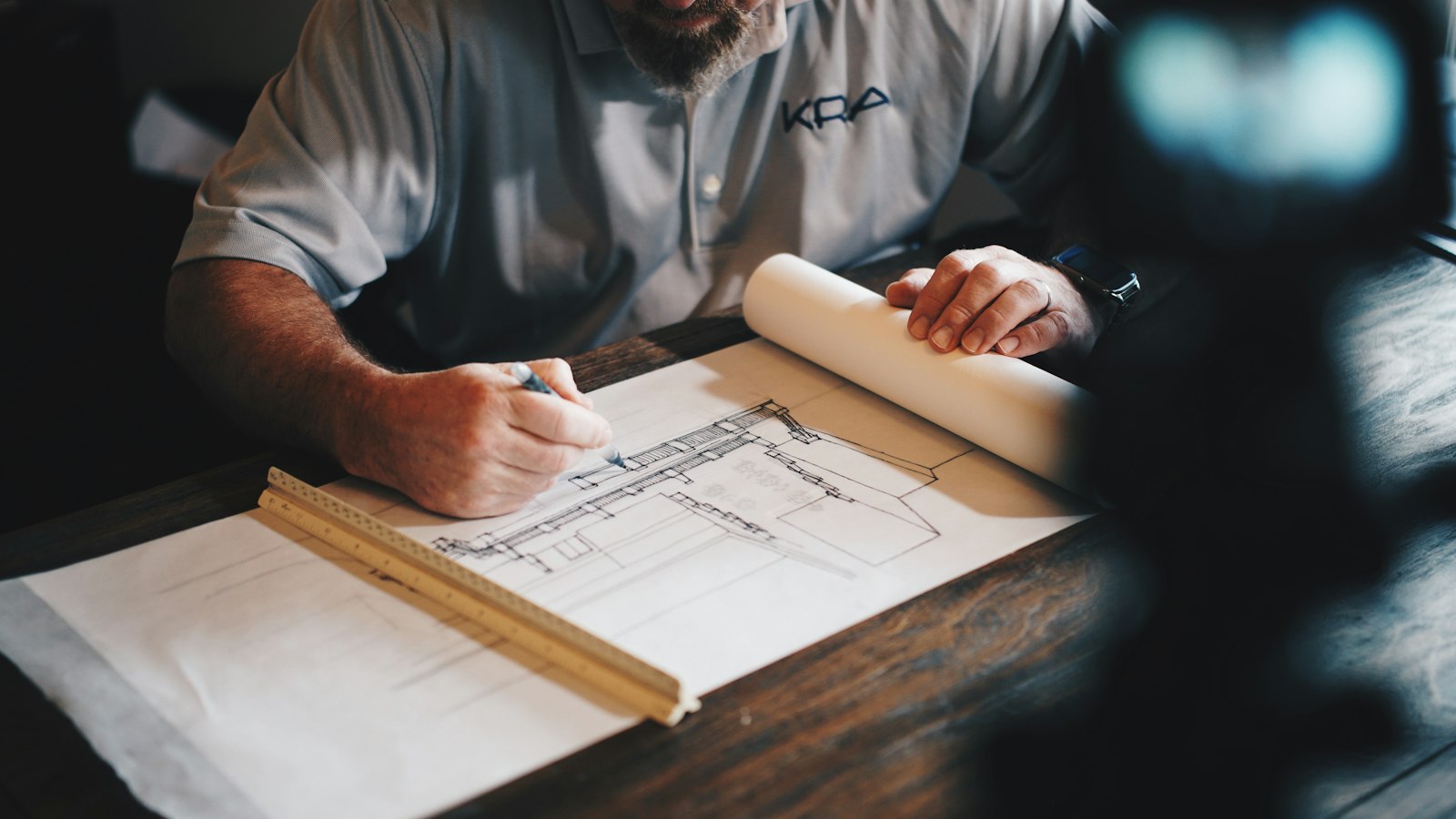 A person marking measurements on architectural drawings at a desk